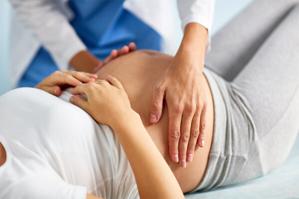 Care proviver palpating a pregnant belly
