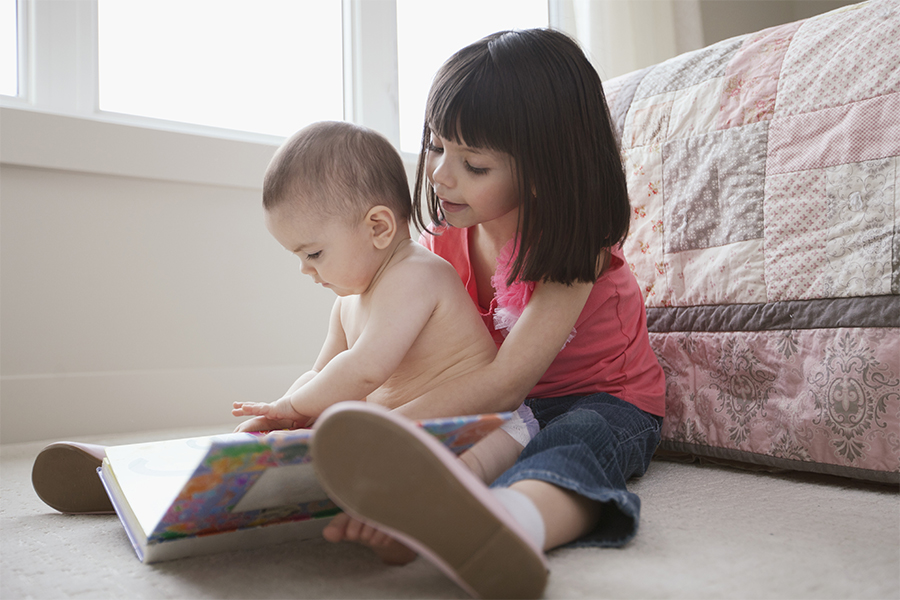 Little girl reading to a new baby
