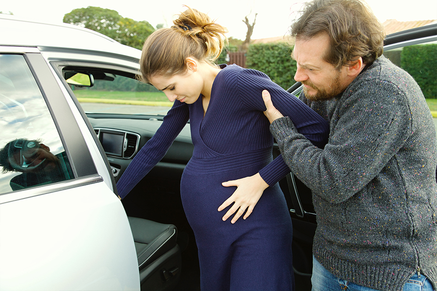 Pregnant woman and partner getting into a car